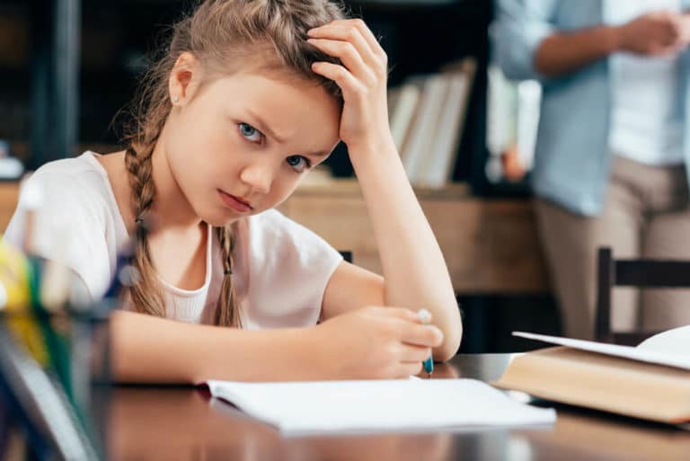 Bild zeigt ein Kind, das unmotiviert an den Hausaufgaben sitzt